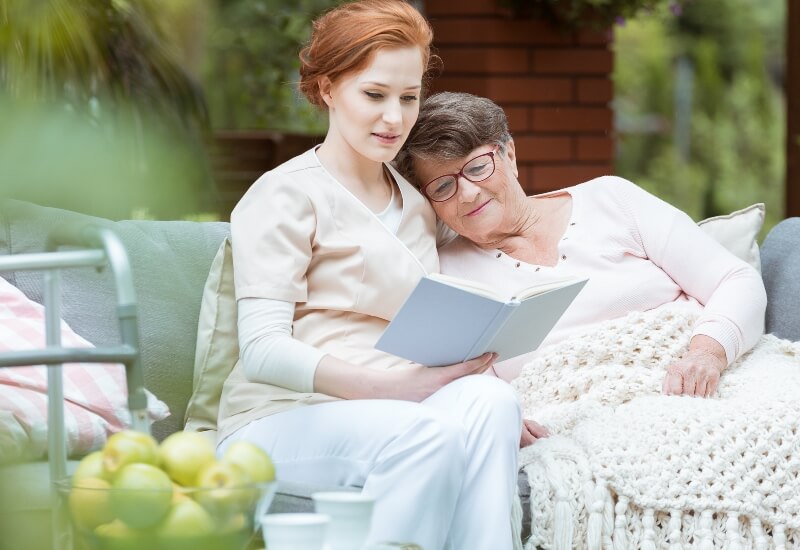 hospice volunteer reading to a patient in a garden