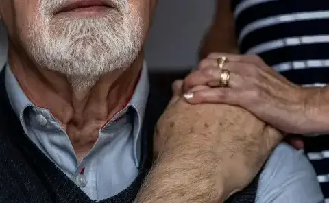 A caretaker comforts a man with Alzheimer's Disease at his home in Portland, OR