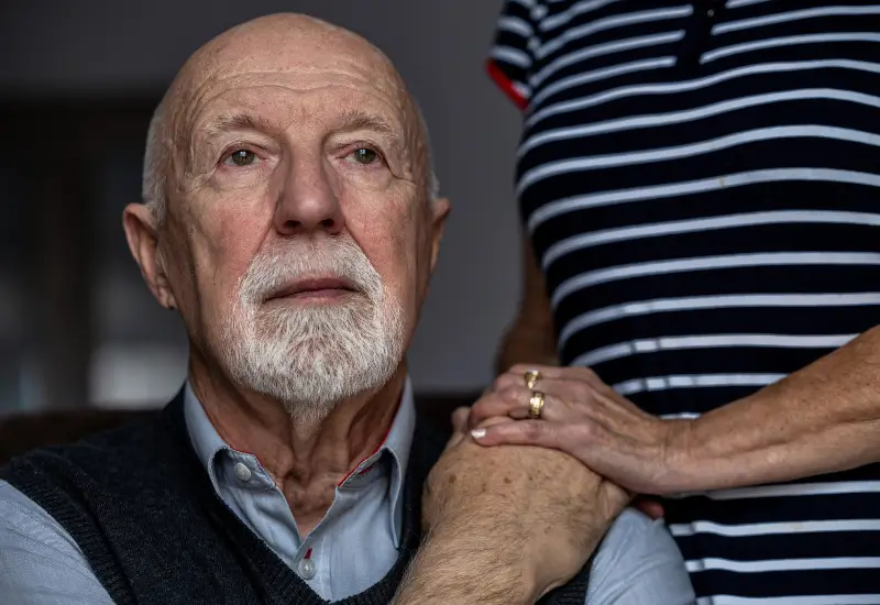 A caretaker comforts a man with Alzheimer's Disease at his home in Portland, OR