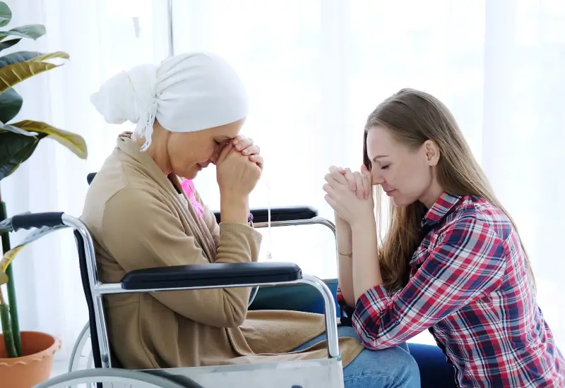 A hospice patient with cancer prays with a loved one