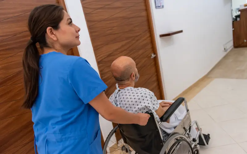 A hospital worker brings a man in a wheelchair 