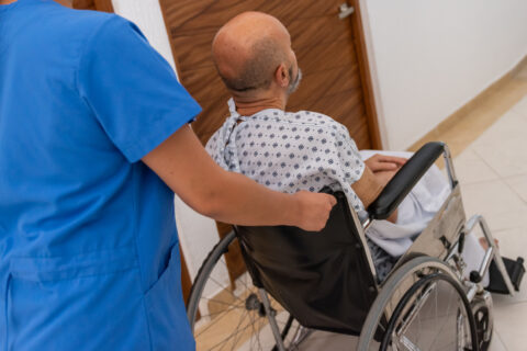 A hospital worker brings a man in a wheelchair